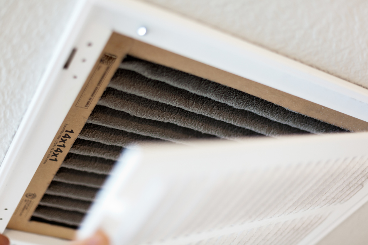 Close-up of a person changing an HVAC air filter on the ceiling.